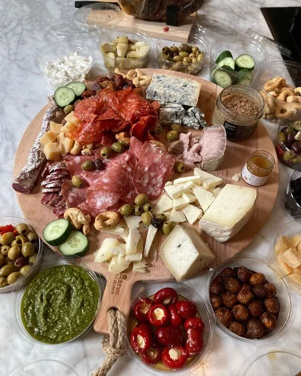 Ronde borrelplank met vleeswaren, kazen, olijven, pesto, tomaatjes en taralli