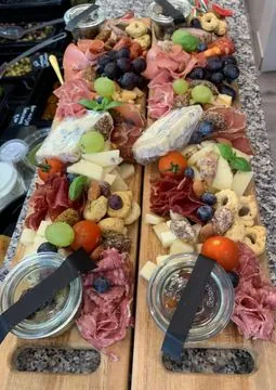 Twee lange borrelplanken met vleeswaren, kaas, druiven, tomaatjes en taralli