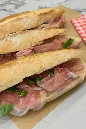 Drie broodjes parma met parmaham en basilicum op inpakpapier