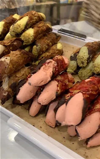Cannoli met pistache, chocolade en roze crème in de vitrine