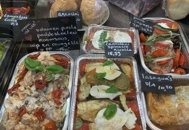 Afhaalmaaltijden in bakjes in de vitrine, met krijtbordjes ernaast