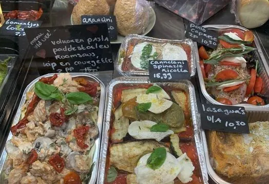 Afhaalmaaltijden in bakjes in de vitrine, met krijtbordjes ernaast