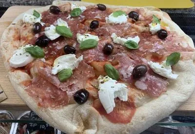 Verse pizza met prosciutto, mozzarella, olijven en basilicum