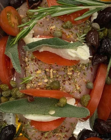 Pollo caprese in een ovenschaal: kip met tomaat, mozzarella, salie en rozemarijn, klaar om op te warmen