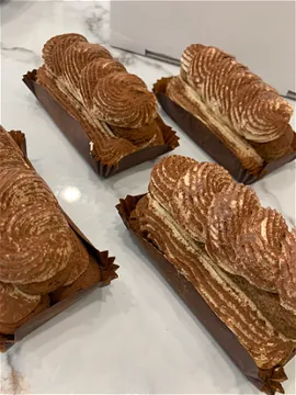 Vier porties tiramisu in papieren bakjes op marmer