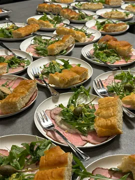 Een tafel vol bordjes vitello tonnato met rucola en focaccia